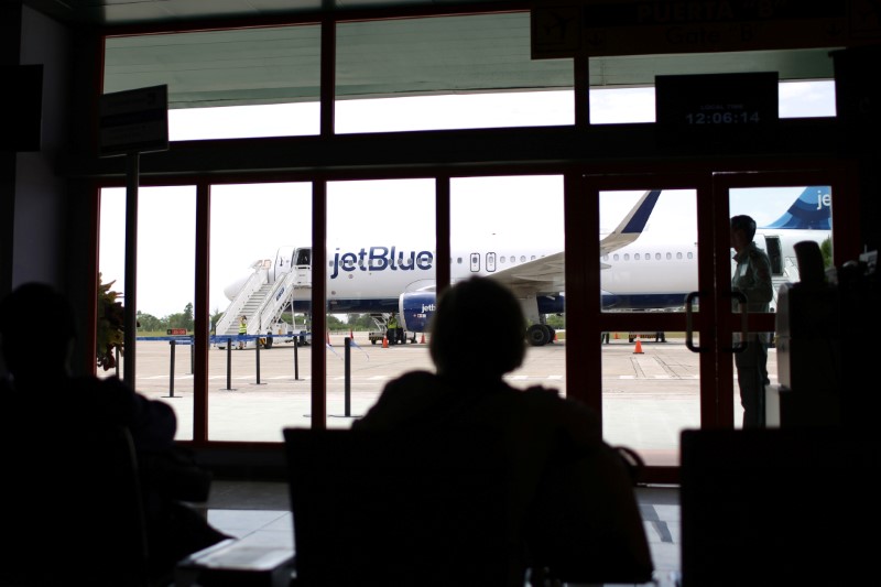 © Reuters. Passengers wait to board an airplane as a just landed JetBlue aeroplane, the first commercial scheduled flight between the United States and Cuba in more than 50 years, is seen at the Abel Santamaria International Airport in Santa Clara, Cuba