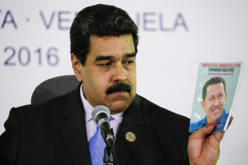 © Reuters. Venezuela's President Maduro holds a book with a photo of Venezuela's late President Chavez as he talks to the media during a news conference after the 17th Non-Aligned Summit in Porlamar
