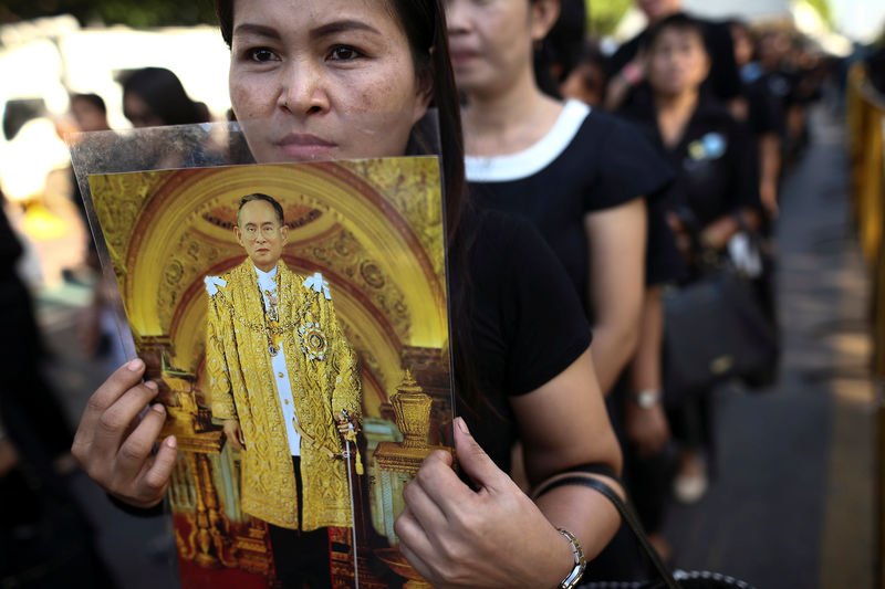 © Reuters. A mourner holds up a picture of Thailand's late King Bhumibol as she waits in line to offer condolences at the Grand Palace in Bangkok