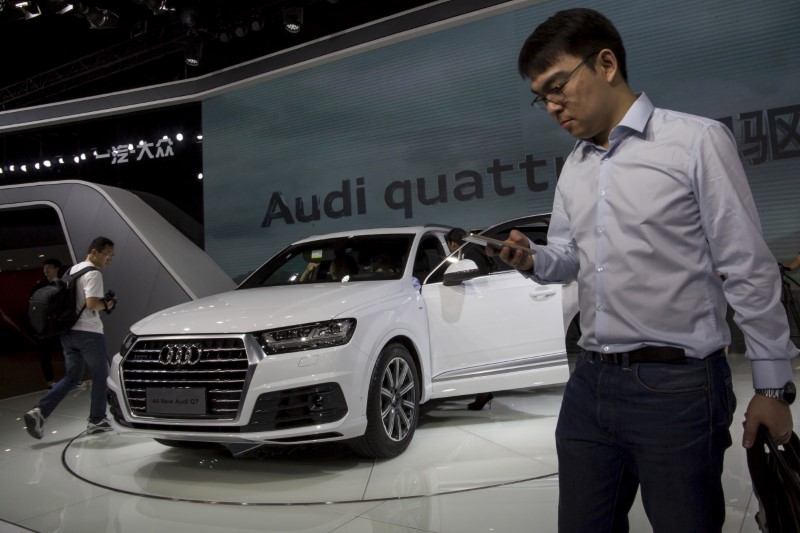 © Reuters. People walk past a Audi new Q7 car at the 13th China (Guangzhou) International Automobile Exhibition in Guangzhou, China