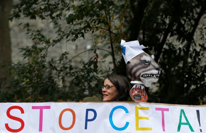 © Reuters. A protester holds a banner reading "Stop CETA" during a protest outside the Walloon regional parliament in Namur