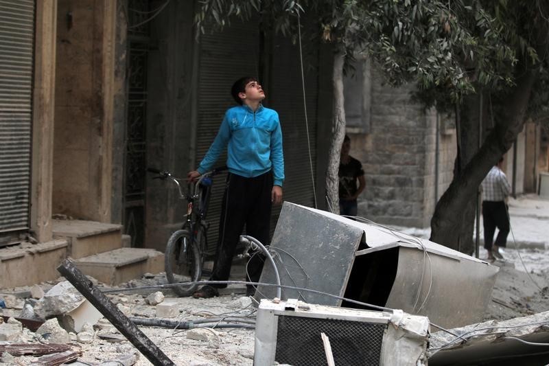 © Reuters. A youth inspects a damaged site after an airstrike in the besieged rebel-held al-Qaterji neighbourhood of Aleppo