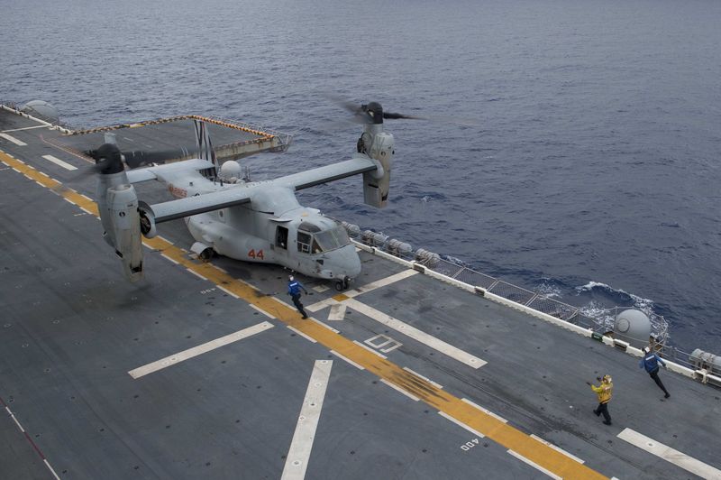 © Reuters. A landing signalman directs an Osprey aircraft to land on flight deck of the amphibious assault ship USS Bonhomme Richard in South China Sea