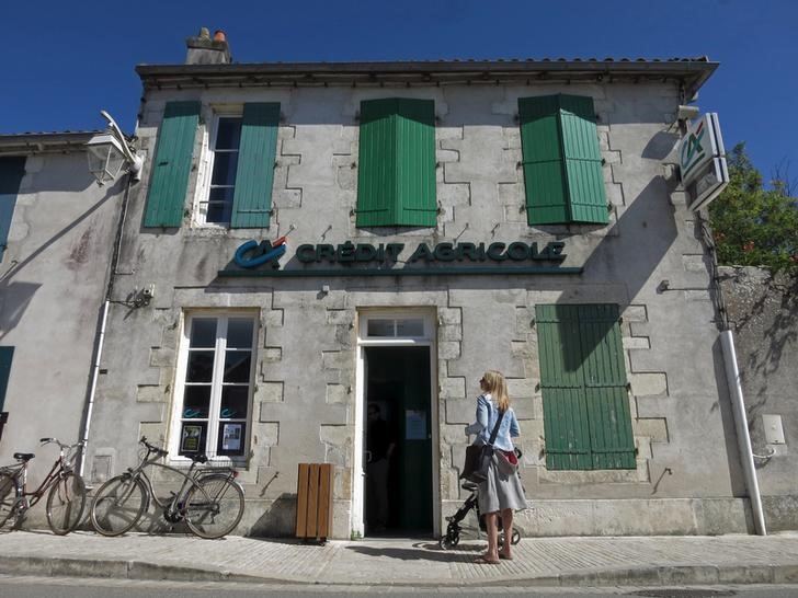© Reuters. A woman stands outside a branch of French bank Credit Agricole in Ars-en-Re on the Ile de Re