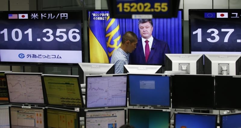 © Reuters. Employee of a foreign exchange trading company walks past a monitor showing Ukrainian President Poroshenko, in Tokyo
