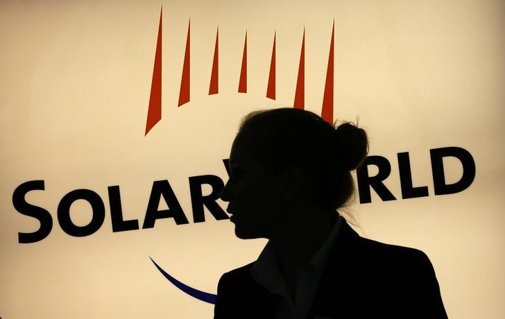 © Reuters. A woman is silhouetted against the logo of Germany's SolarWorld at the reception desk of the company's  extraordinary shareholders meeting in Bonn