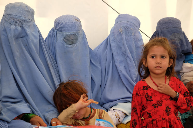 © Reuters. Afghan women, who were living as refugees in Pakistan, wait with their children at a humanitarian aid centre after their return, in Torkham, Afghanistan