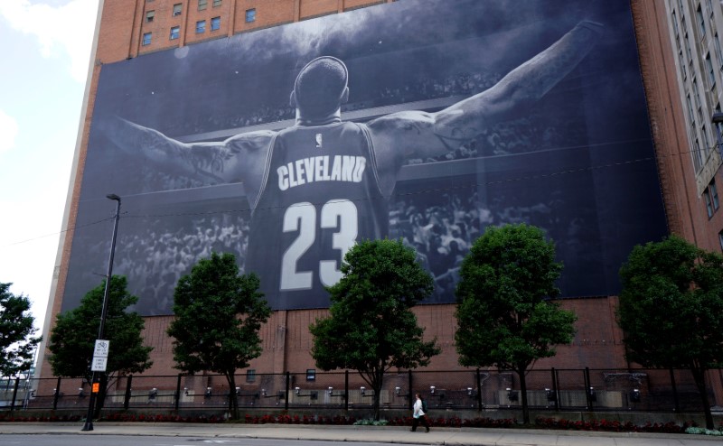 © Reuters. A woman on the sidewalk is dwarfed by a giant picture of NBA basketball Cleveland Cavaliers player LeBron James in downtown Cleveland across the street from the Republican National Convention