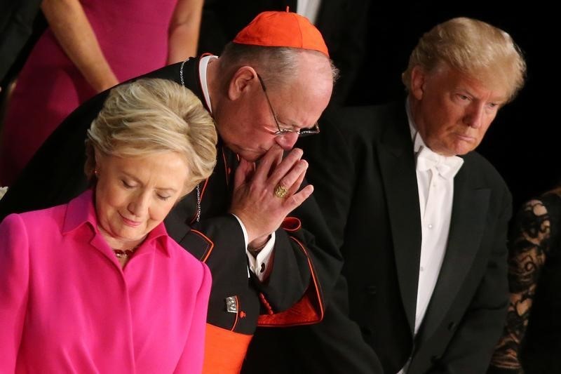 © Reuters. Democratic U.S. presidential nominee Clinton, Archbishop of New York Cardinal Dolan and Republican U.S. presidential nominee Trump pray during the Alfred E. Smith Memorial Foundation dinner in New York