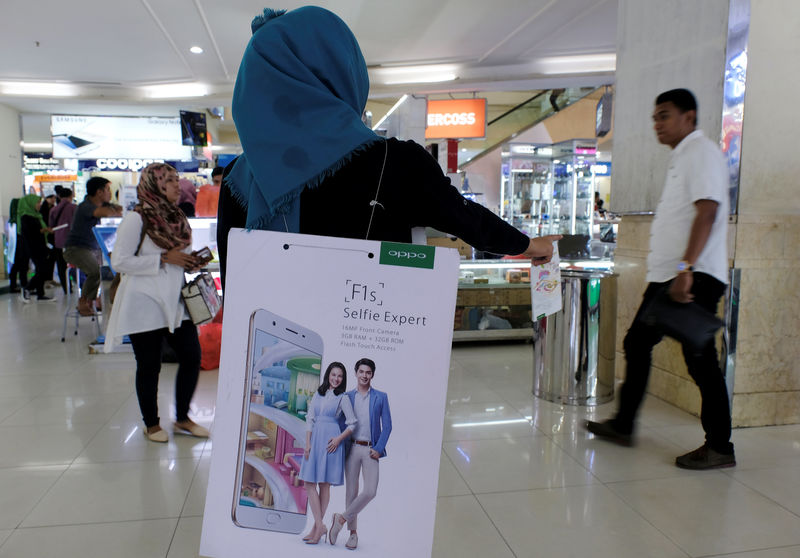 © Reuters. A salesperson promotes OPPO smartphones to customers at ITC Roxymas shopping mall in Jakarta