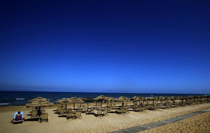 © Reuters. A German tourist sits on a sunbed on the beach of the Olympia Riviera resort in the town of Killini