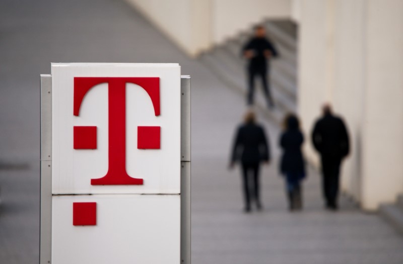 © Reuters. People walk past the logo of German telecommunications giant Deutsche Telekom AG seen at the Telekom's headquarters in Bonn