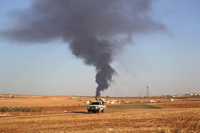 © Reuters. Rebel fighters ride a military vehicle near rising smoke from al-Bab city, northern Aleppo province