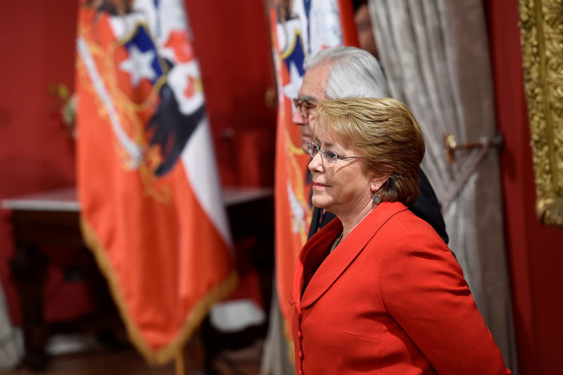© Reuters. Chilean President Michelle Bachelet stands next to Interior Minister Mario Fernandez during a cabinet reshuffle at the government house in Santiago