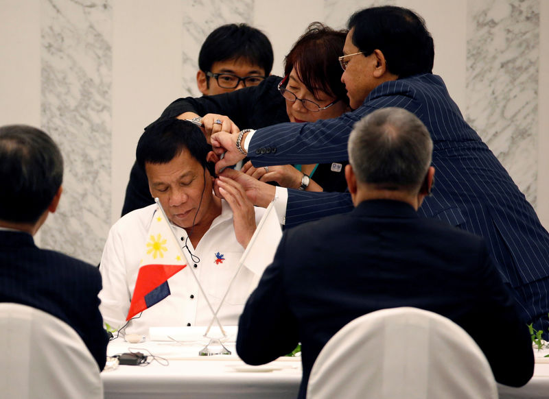 © Reuters. Philippine President Rodrigo Duterte is helped by interpreters to attach an earphone as he attends a luncheon meeting with Japanese business leaders in Tokyo