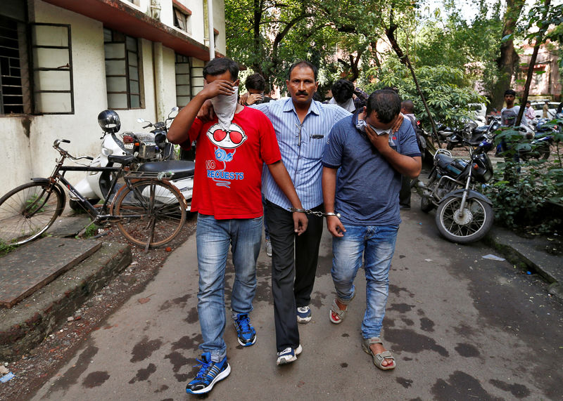 © Reuters. A policeman escorts men who they said were arrested on Wednesday on suspicion of tricking American citizens into sending them money by posing as U.S. tax officials, at a court in Thane