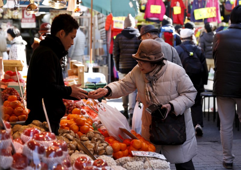 © Reuters. A woman pays money as she buys fruits outside a vegetable store at Ameyoko shopping district in Tokyo