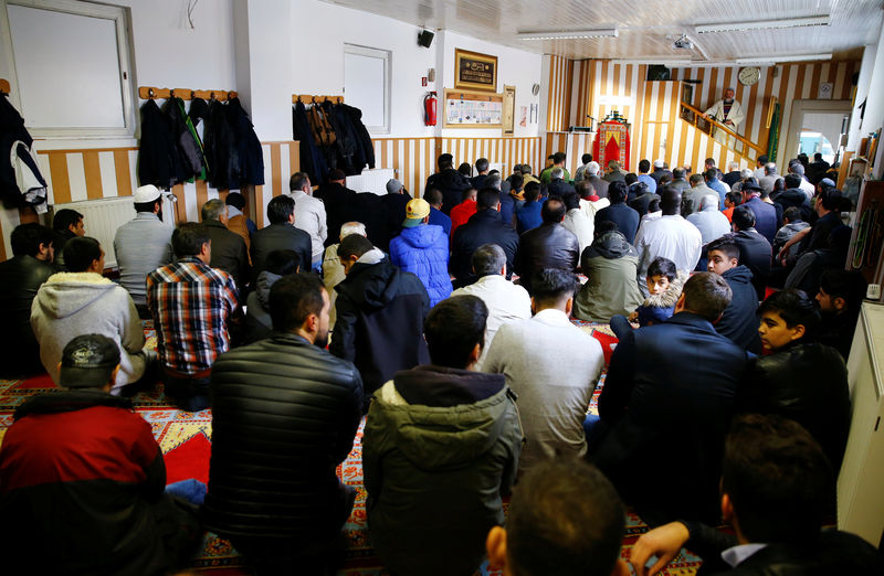 © Reuters. Muslims listen to a Turkish imam during Friday prayers at the Turkish Kuba Camii mosque located near a hotel housing refugees in Cologne's district of Kalk