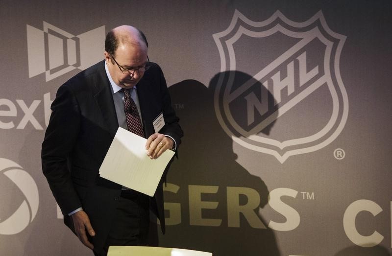 © Reuters. Rogers Communications Inc President and CEO Laurence walks by an NHL logo at an AGM in Toronto