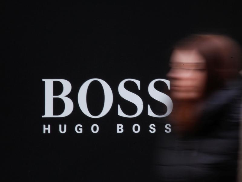© Reuters. A woman walks past Hugo Boss store logo on a shopping center at the outlet village Belaya Dacha outside Moscow