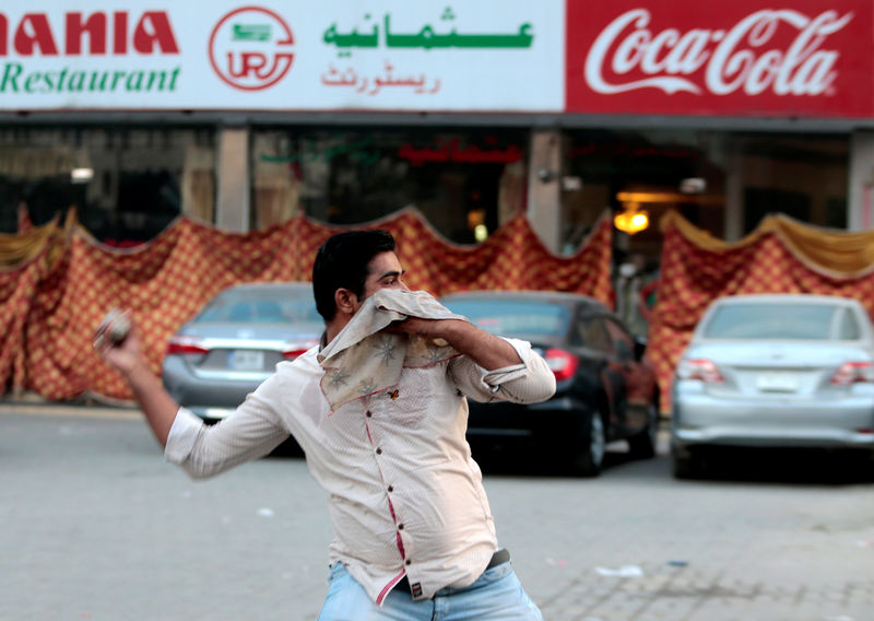 © Reuters. A protester throws stones at police during clashes in Rawalpindi