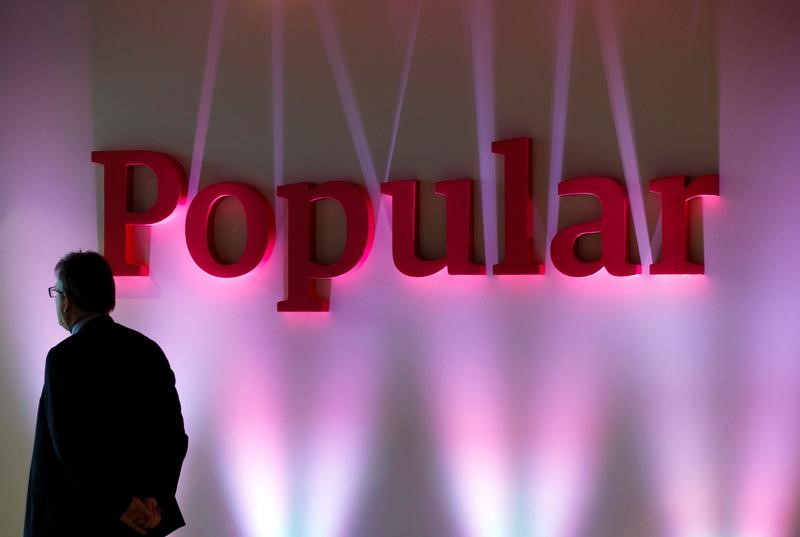 © Reuters. A man stands next to the logo of Spain's Banco Popular during the bank's results presentation in Madrid