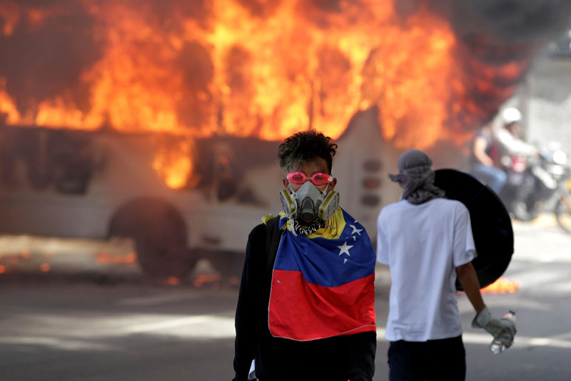 © Reuters. Manifestantes ao lado de um ônibus em chamas durante protesto contra o governo do presidente da Venezuela, Nicolás Maduro, em Caracas