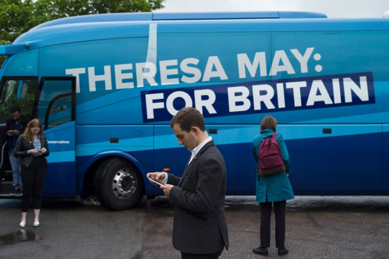 © Reuters. Membros da equipe do Partido Conservador e jornalistas em frente a ônibus de campanha da legenda, em Birmingham