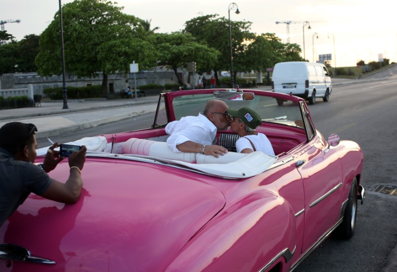 © Reuters. Tourists pose for a photo while sitting in a vintage car in Havana