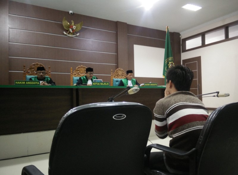 © Reuters. An Indonesian man sits in an Islamic court, one of the two men sentenced to 85 lashes of the cane for having sex together, in Banda Aceh, Indonesia