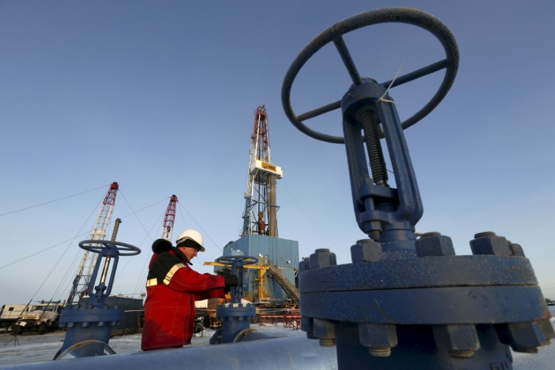© Reuters. FILE PHOTO: File photo of worker checking valve of oil pipe at Lukoil company owned Imilorskoye oil field outside West Siberian city of Kogalym