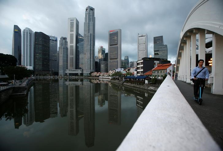 © Reuters. A man passes the skyline of the central business district on a portable scooter