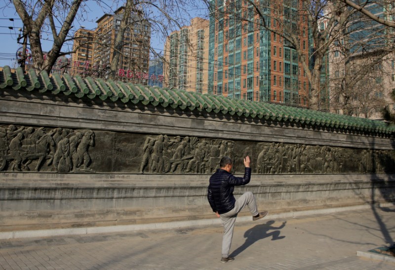 © Reuters. FILE PHOTO: A resident practices Taiji, a traditional form of Chinese martial arts, near apartment blocks in central Beijing