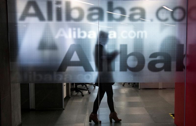 © Reuters. An employee is seen behind a glass wall with the logo of Alibaba at the company's headquarters on the outskirts of Hangzhou, Zhejiang province