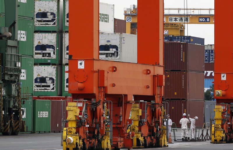 © Reuters. Workers are seen in a container area at a port in Tokyo