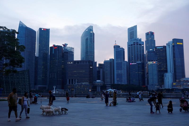 © Reuters. People walk past the skyline of the central business district along the Marina Bay Promenade in Singapore
