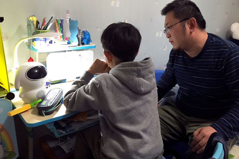© Reuters. 8-year-old Hu Yizhuo does his homework with his father Hu Chengyu in Nanjing