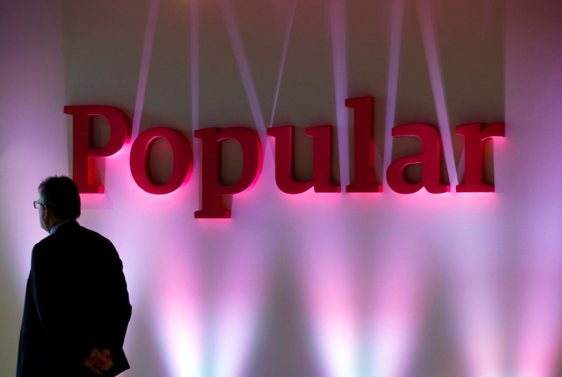 © Reuters. FILE PHOTO: A man stands next to the logo of Spain's Banco Popular during the bank's results presentation in Madrid