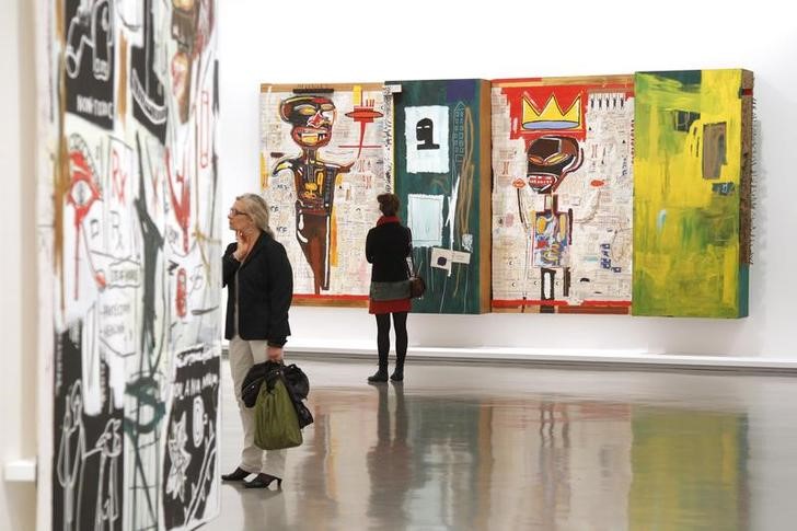 © Reuters. Visitantes observan las telas del artista, Jean-Michel Basquiat, en el Museo de Arte Moderno en París, Francia.