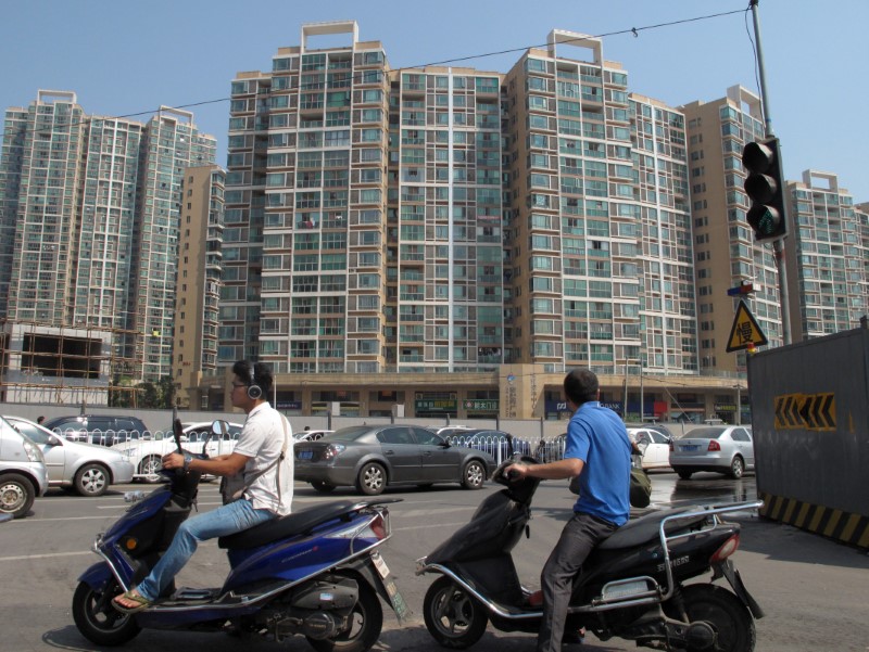 © Reuters. People ride past a residential complex Changsha