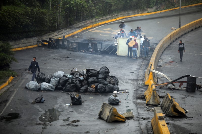 © Reuters. Un hombre camina al lado de la barricada luego de días de protestas contra el presidente venezolano Nicolás Maduro en la ciudad de Los Teques