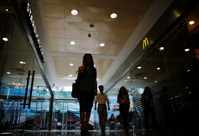 © Reuters. FILE PHOTO: A woman walks next to a McDonald's restaurant and a Starbucks coffee store at a shopping mall in Shanghai