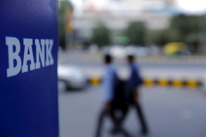 © Reuters. Commuters walk past a bank sign along a road in New Delhi