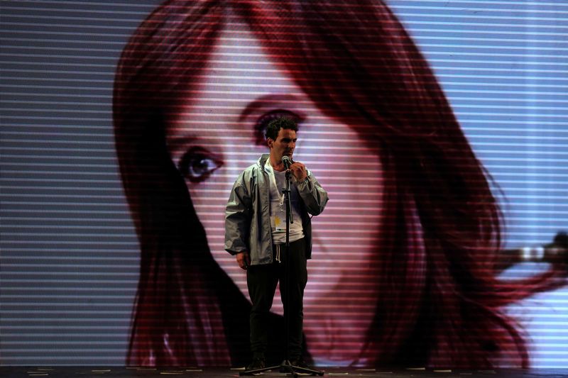 © Reuters. A man tests a microphone in front of a large screen with an image of Cristina Fernandez de Kirchner, former Argentine president and candidate for the Senate in the mid-term primary elections, at her campaign headquarters in Buenos Aires