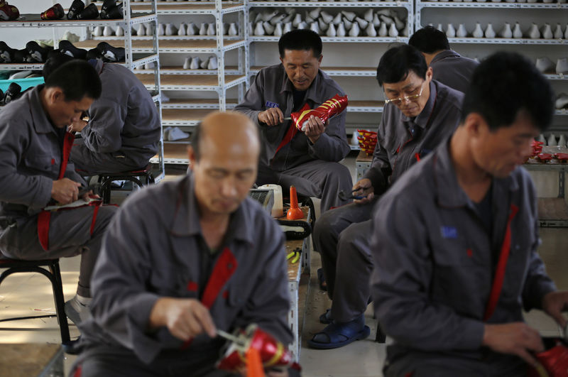 © Reuters. FILE PHOTO - North Korean workers make soccer shoes inside a temporary factory at a rural village on the edge of Dandong