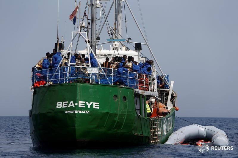 © Reuters. Rescued migrants watch from the deck of the Dutch rescue ship Sea-Eye, as their flooded rubber dinghy with dead bodies in it is tied alongside, after some migrants drowned in the central Mediterranean in international waters off the coast of Libya