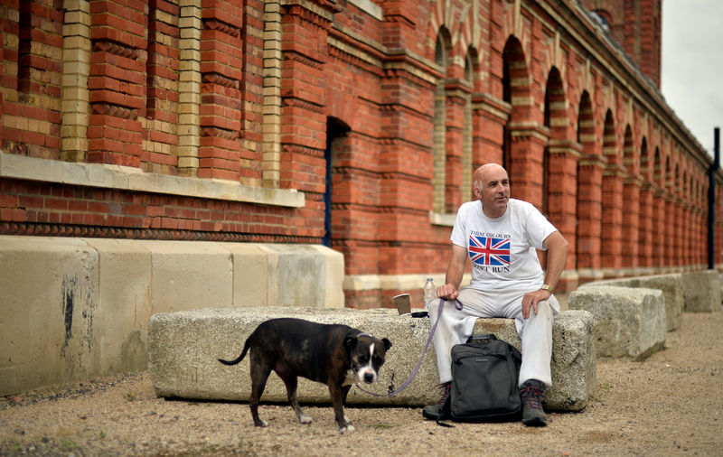 © Reuters. A man sits with his dog outside the Copper Rivet Distillery in Chatham