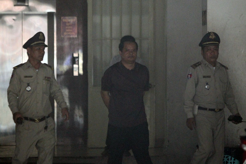 © Reuters. Cambodian politician and government critic Sourn Serey Ratha is escorted by police officers at the Municipal Court of Phnom Penh