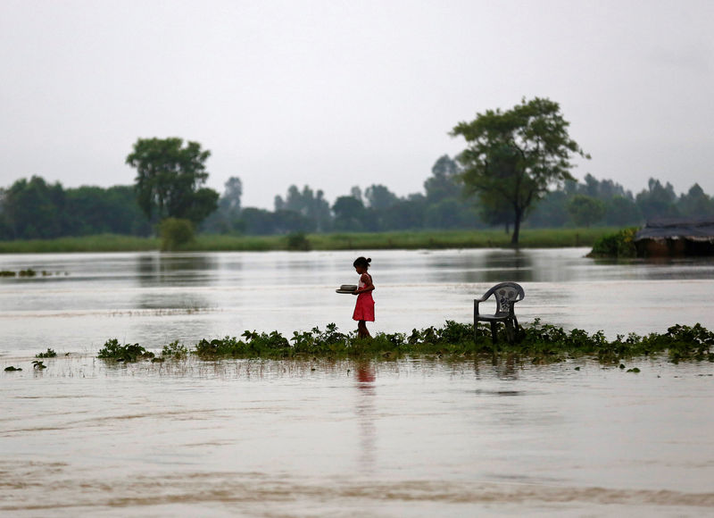 © Reuters. Menina carregando pratos em área alagada em Janakpur, no Nepal