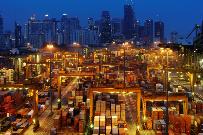 © Reuters. FILE PHOTO: The skyline of Singapore's central business district is seen at dusk as operations continue at a PSA International port terminal in Singapore